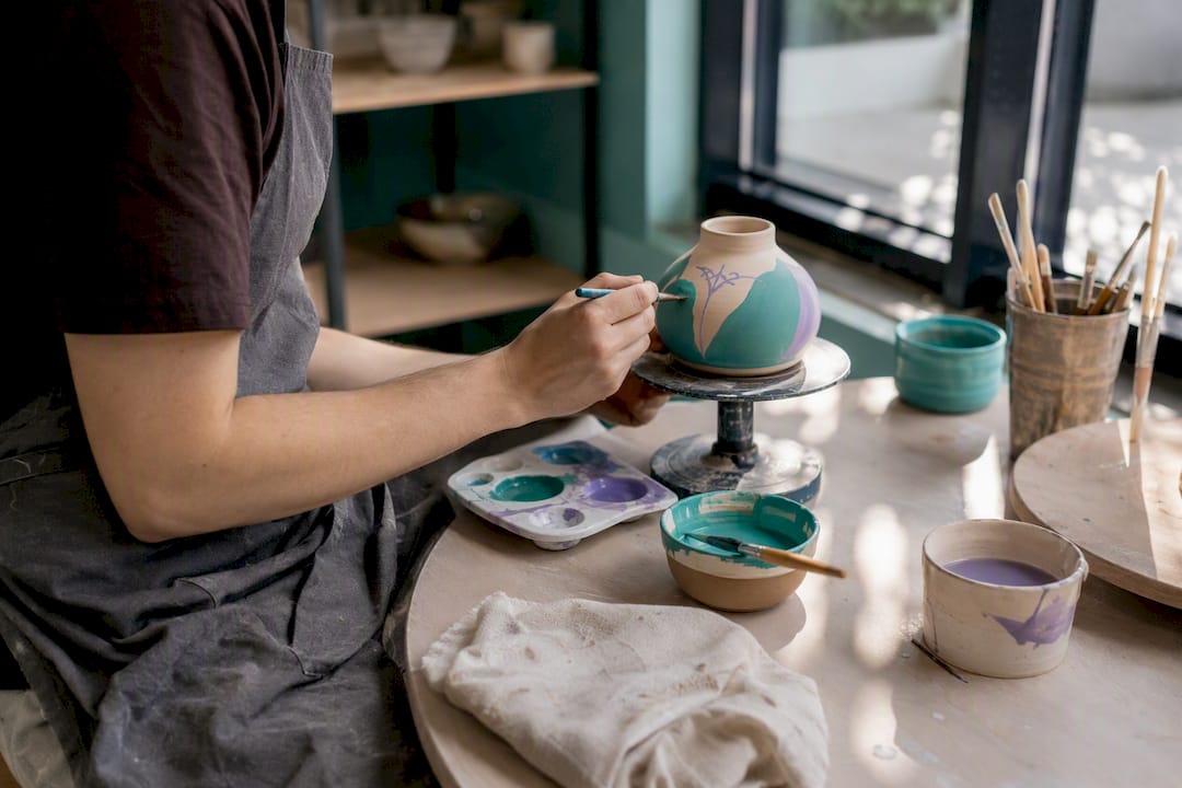 Artist painting ceramic pot in studio