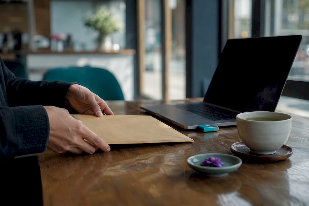 Hands placing secure envelope beside laptop