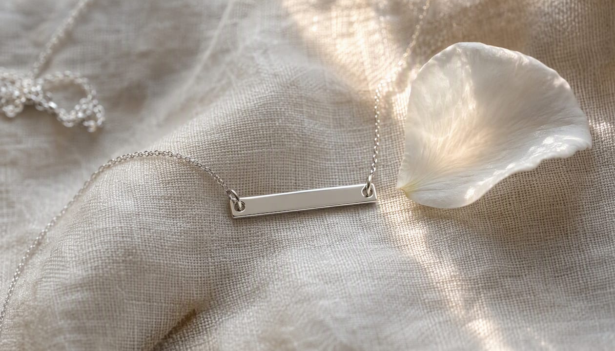 Engraved silver bar necklace on navy fabric
