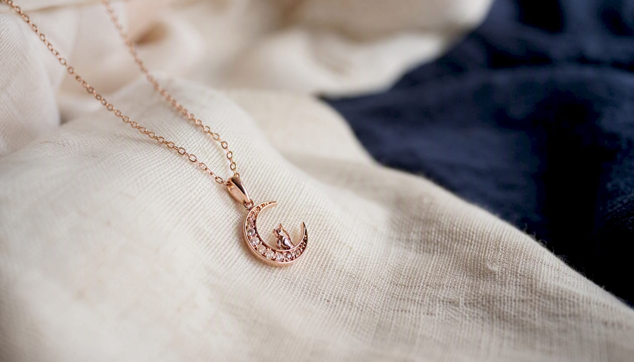 Rose gold crescent moon zodiac necklace on fabric