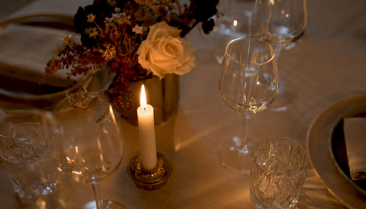Mesa preparada para una cena romántica, iluminada suavemente por la luz de las velas.