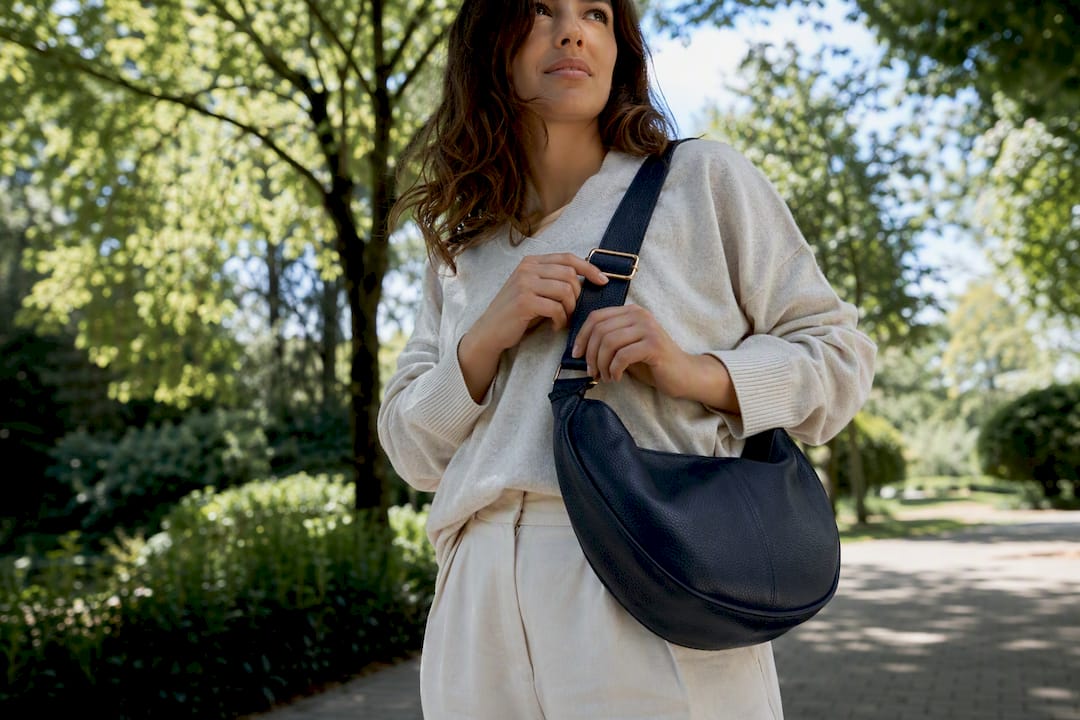 Hands adjusting wide crossbody bag strap