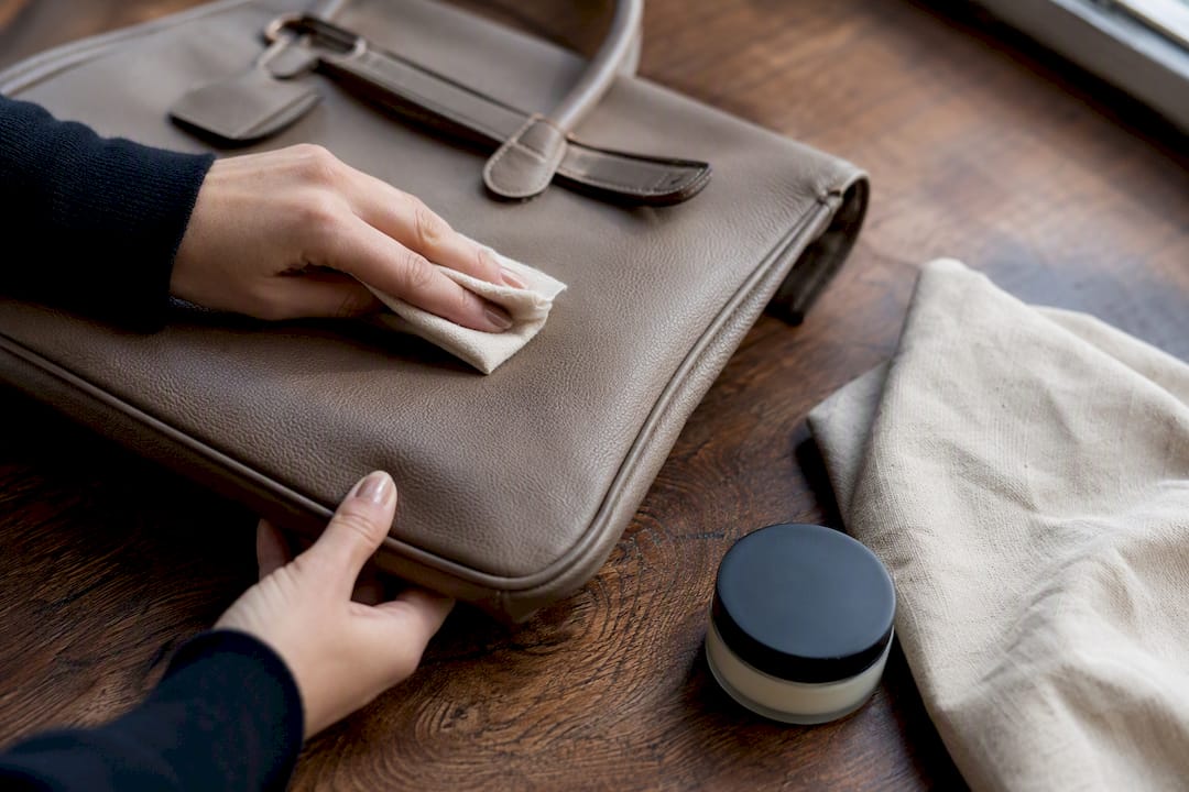 Hand cleaning taupe leather bag