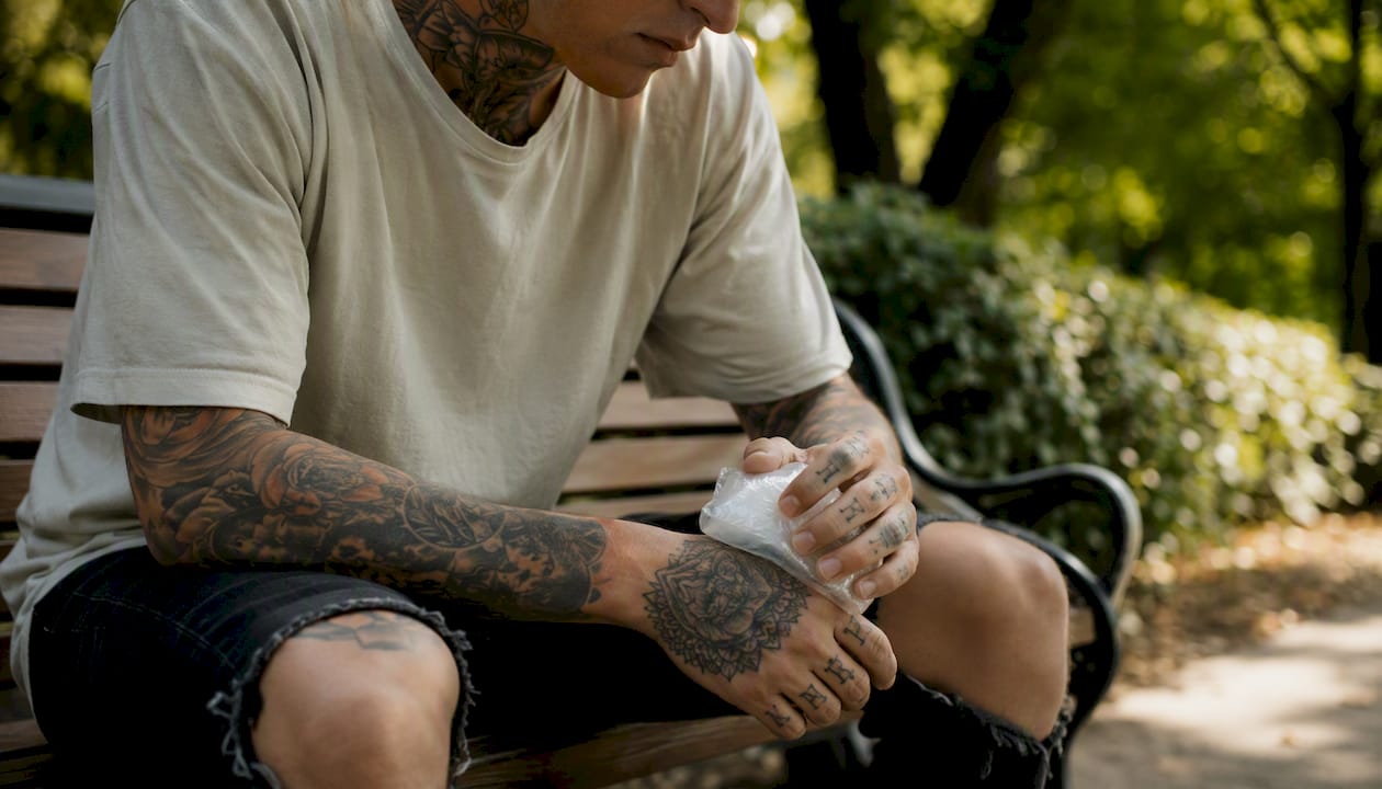 Person applying ice pack on tattooed hand