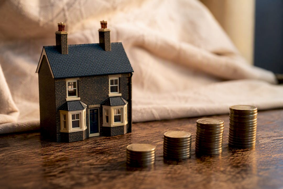 Miniature house with stacked coins representing deposits