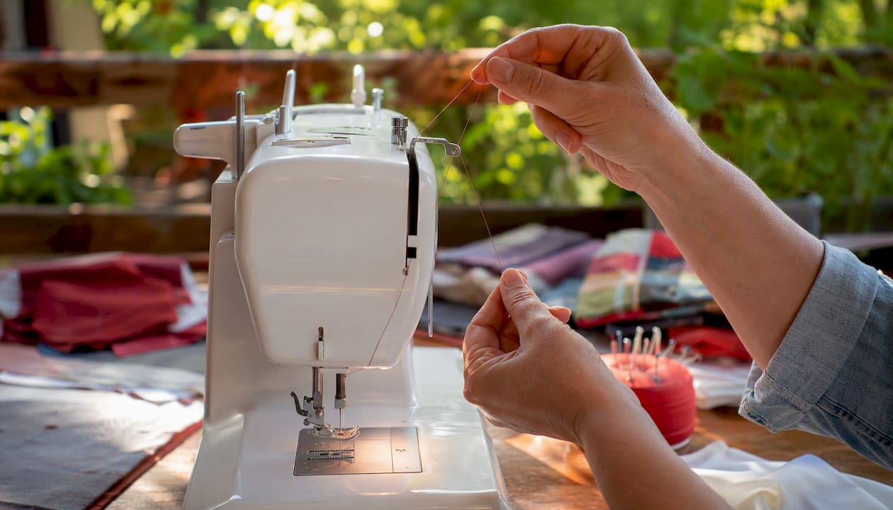 Hands rethreading sewing machine with presser foot raised