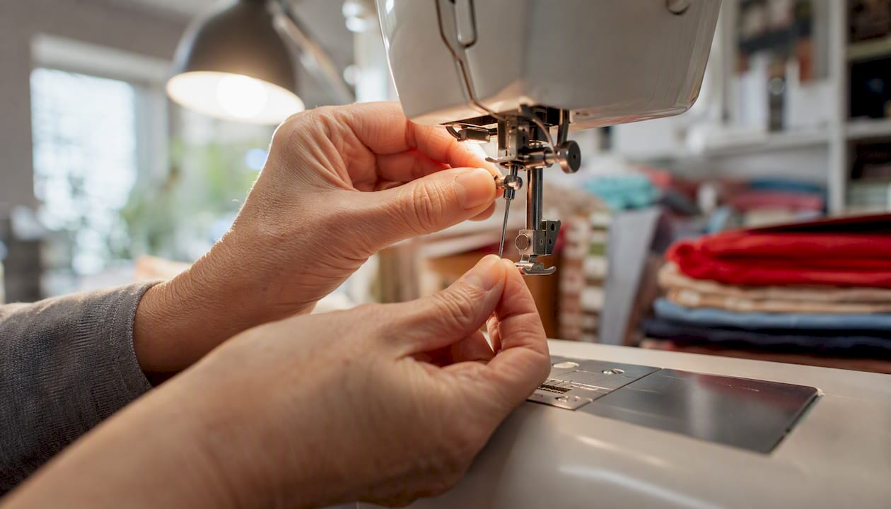 Hands changing sewing machine needle