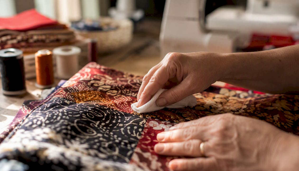 Hands testing batik fabric colorfastness with damp cloth