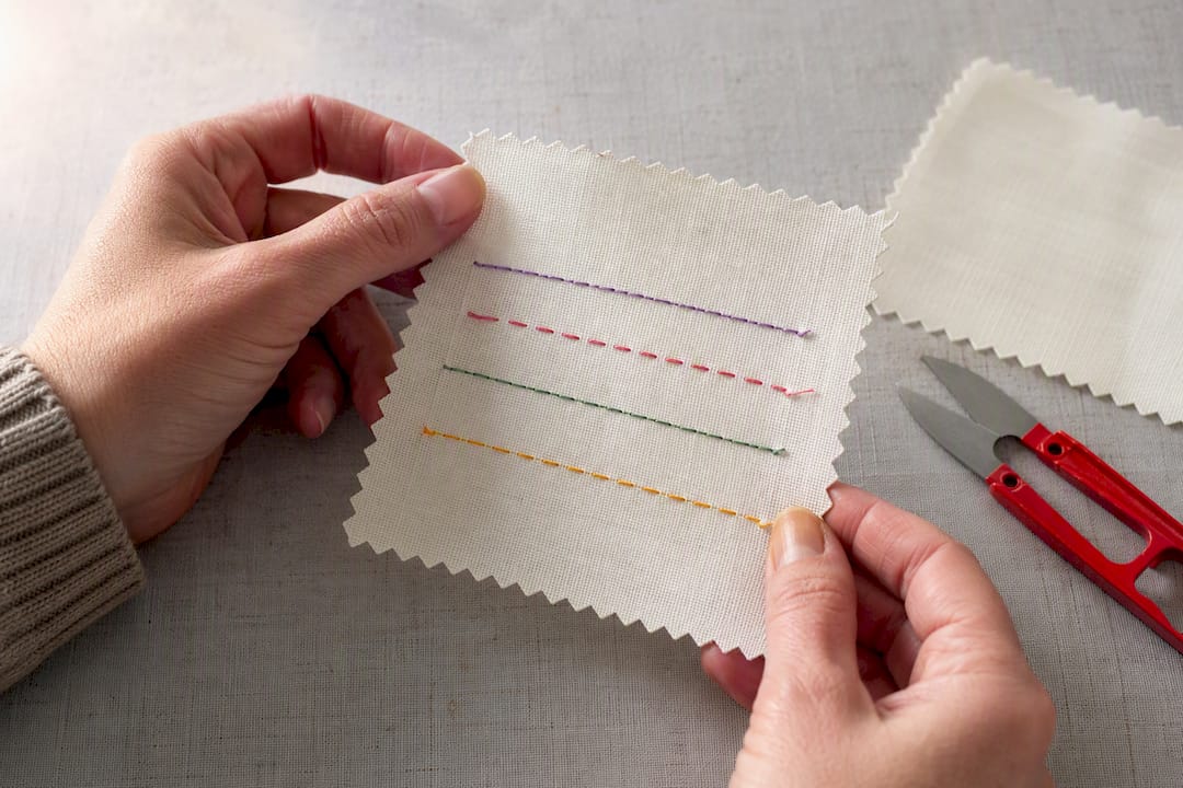 Hands inspecting embroidery sample underside