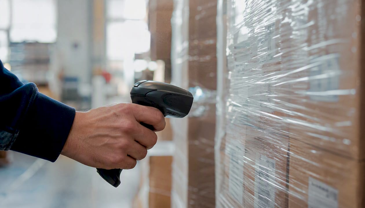 Un operatore passa lo scanner sul codice a barre dei pallet in produzione