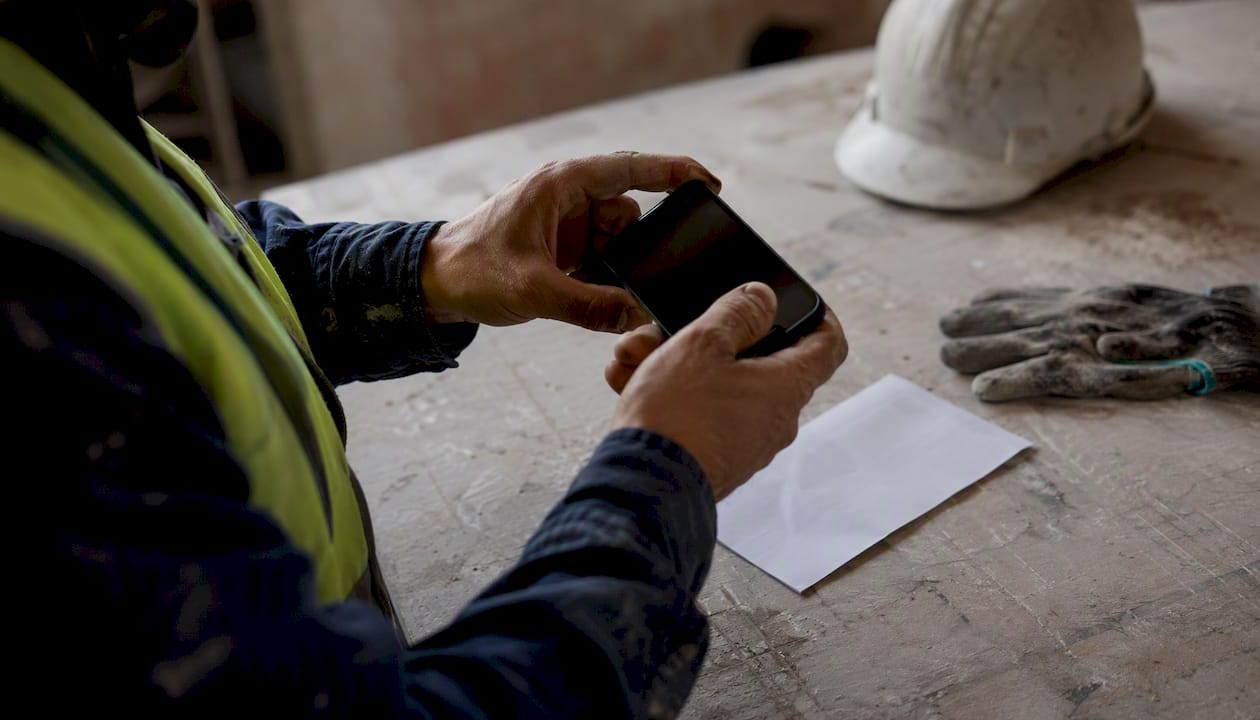 Operaio che scatta una foto dello scontrino con il cellulare direttamente sul posto di lavoro.