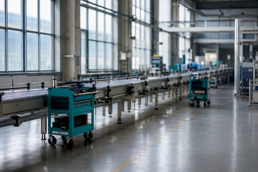 Pavimento di fabbrica vuoto con carrelli per manutenzione e nastri trasportatori