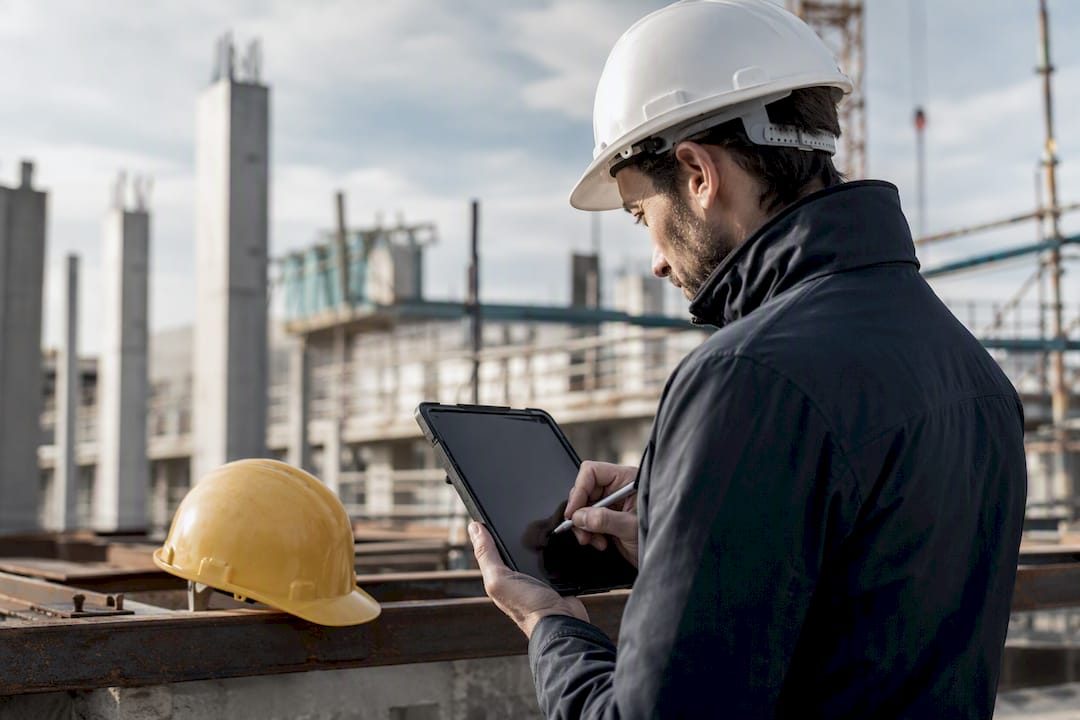 Mani che inseriscono dati su un tablet in cantiere