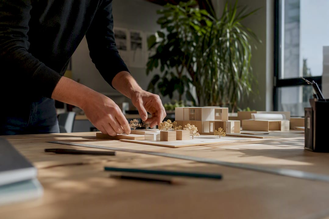 Mani che sistemano modelli di edifici e cartelle in ufficio