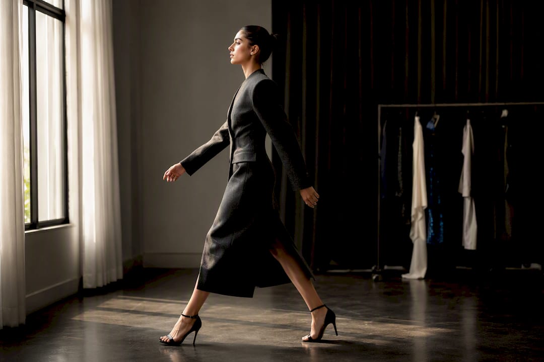 Model rehearsing walk in structured coat and heels