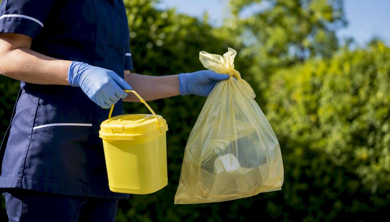 Community nurse carrying clinical waste containers on home visit