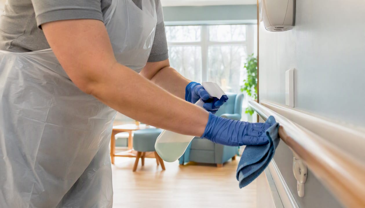 Technician disinfecting door handle in care home