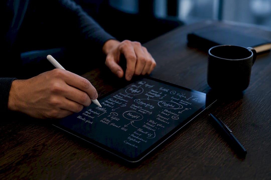 Hands brainstorming app store titles on tablet