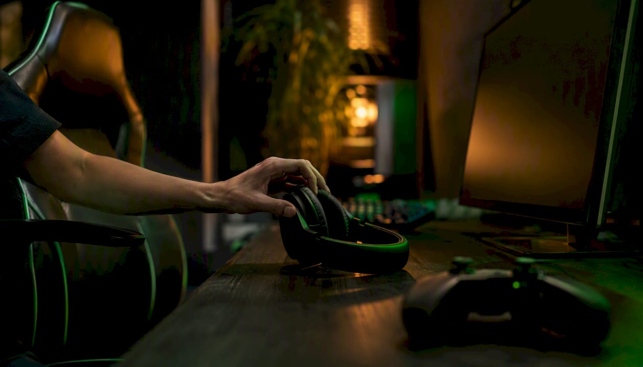 Gamer adjusting headset audio settings in dark setup