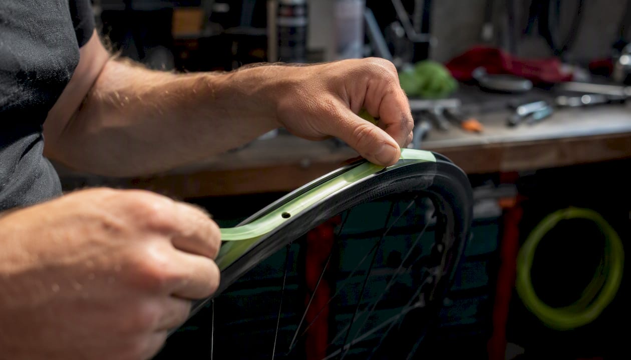 Hands applying tubeless tape to bike rim
