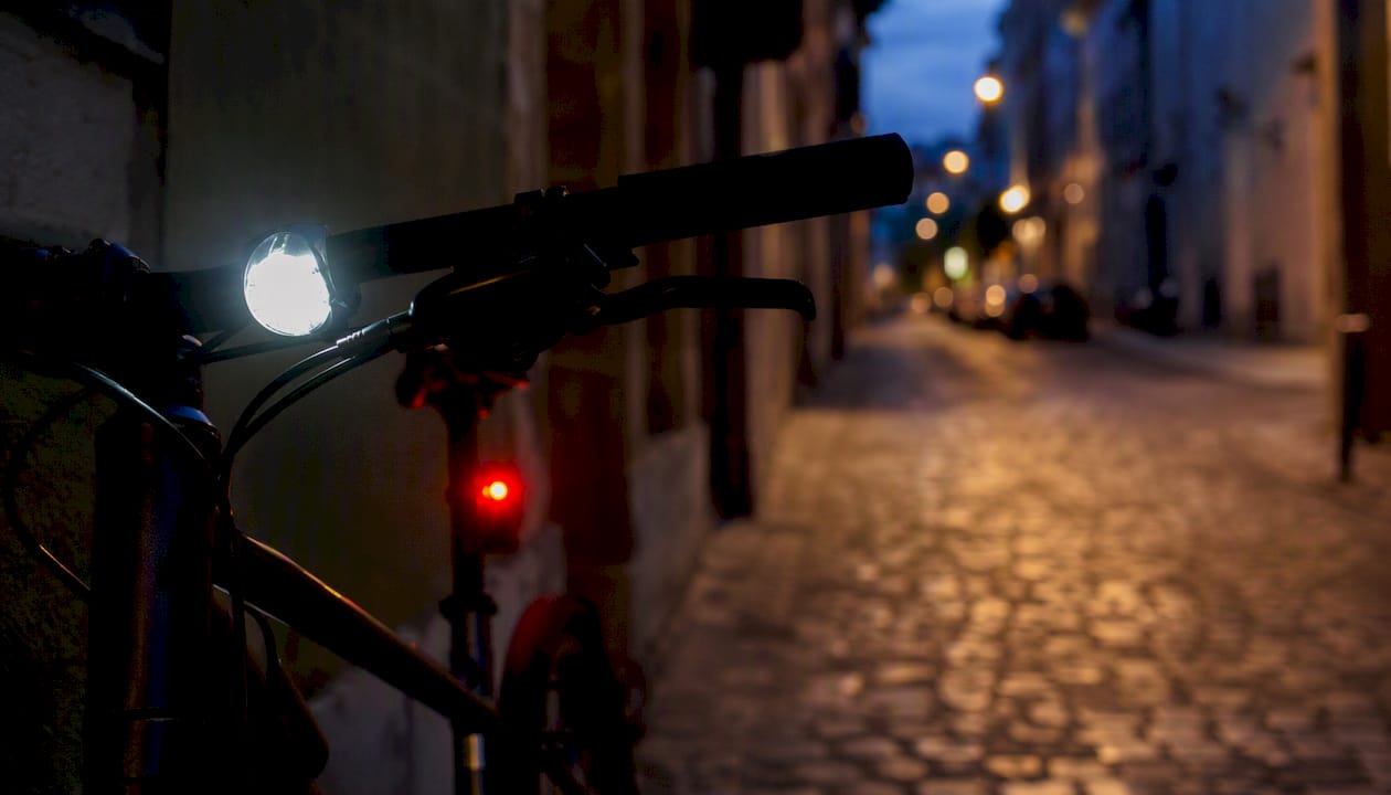 Bike front light illuminating road at dusk, rear red light glowing