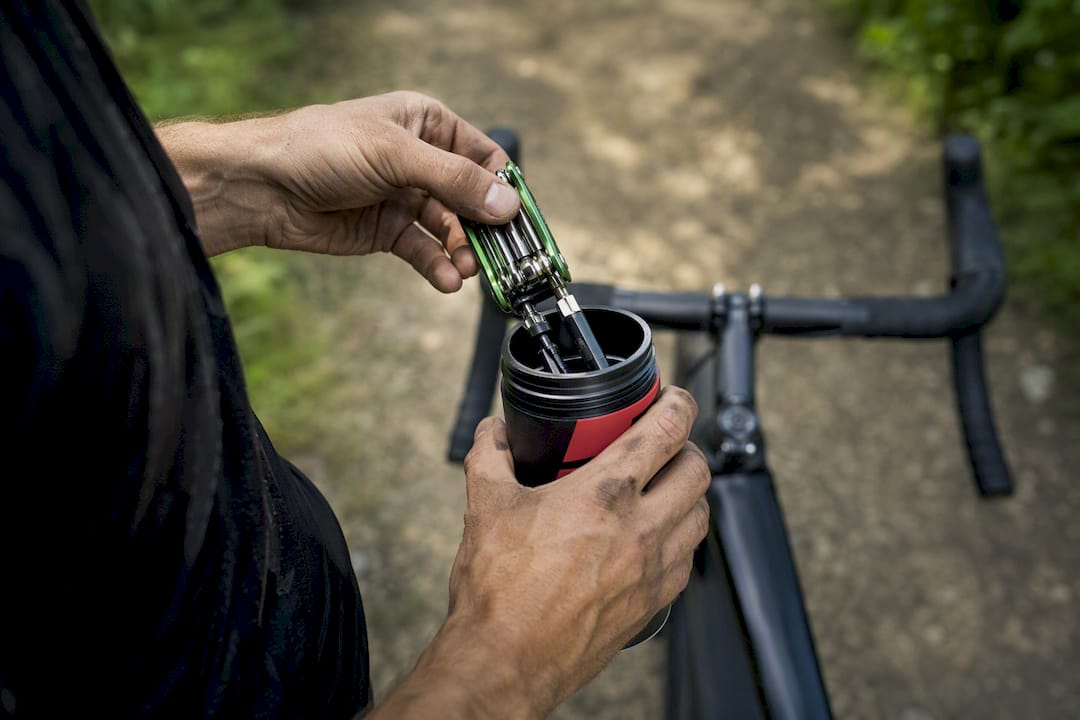 Hands packing cycling tool bottle on bike