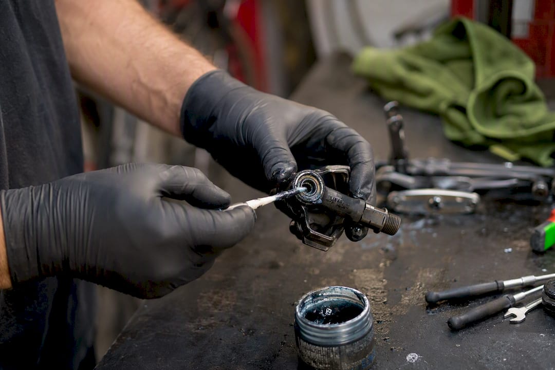 Hands applying grease to SPD pedal bearing