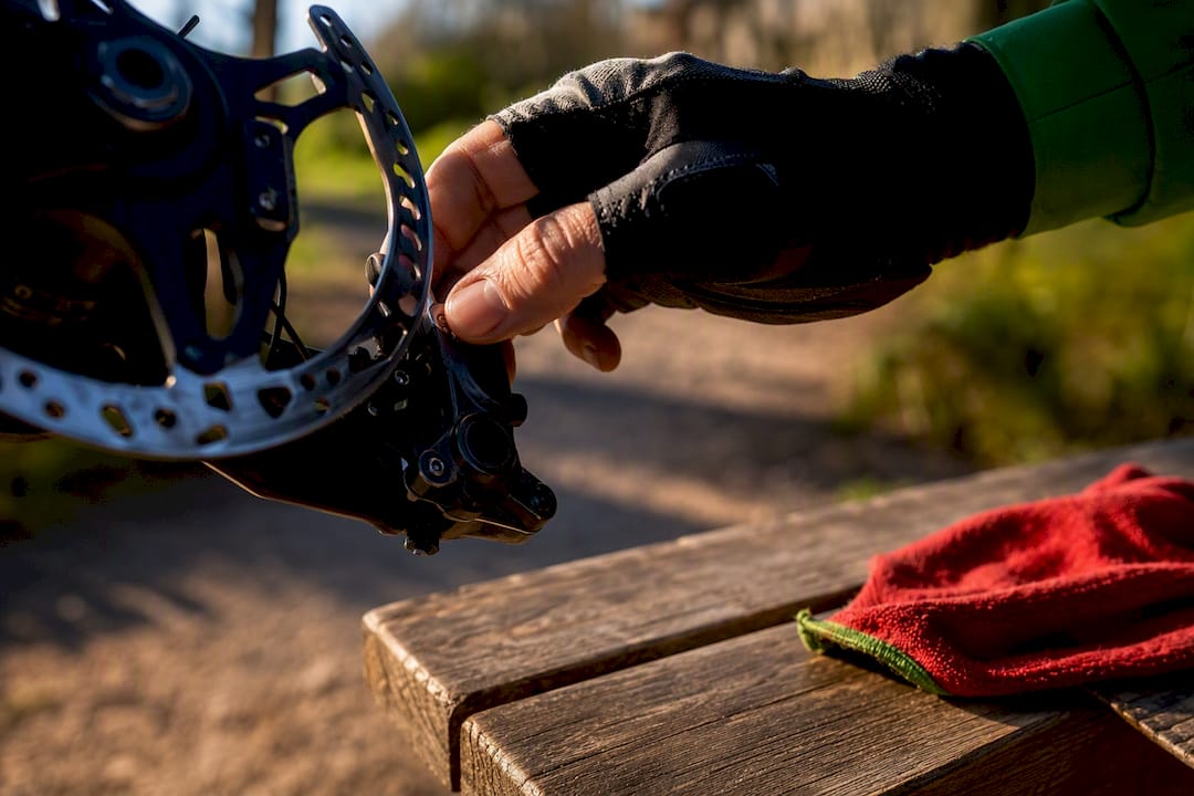 Cyclist inspecting a disc brake before riding