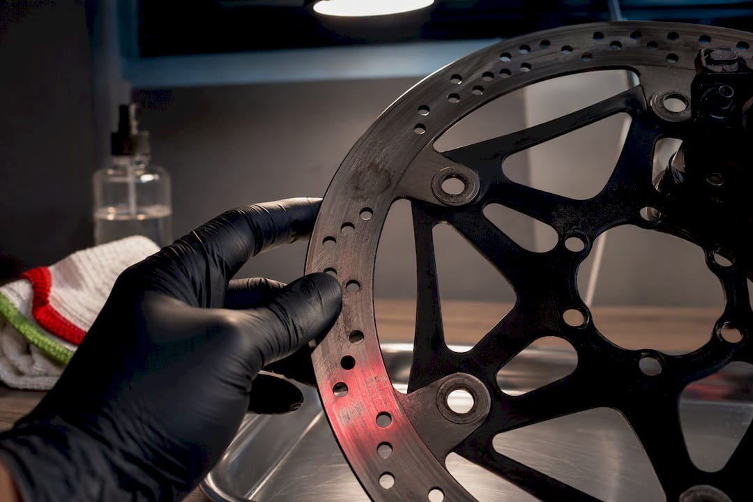 Gloved hand checking a contaminated brake rotor