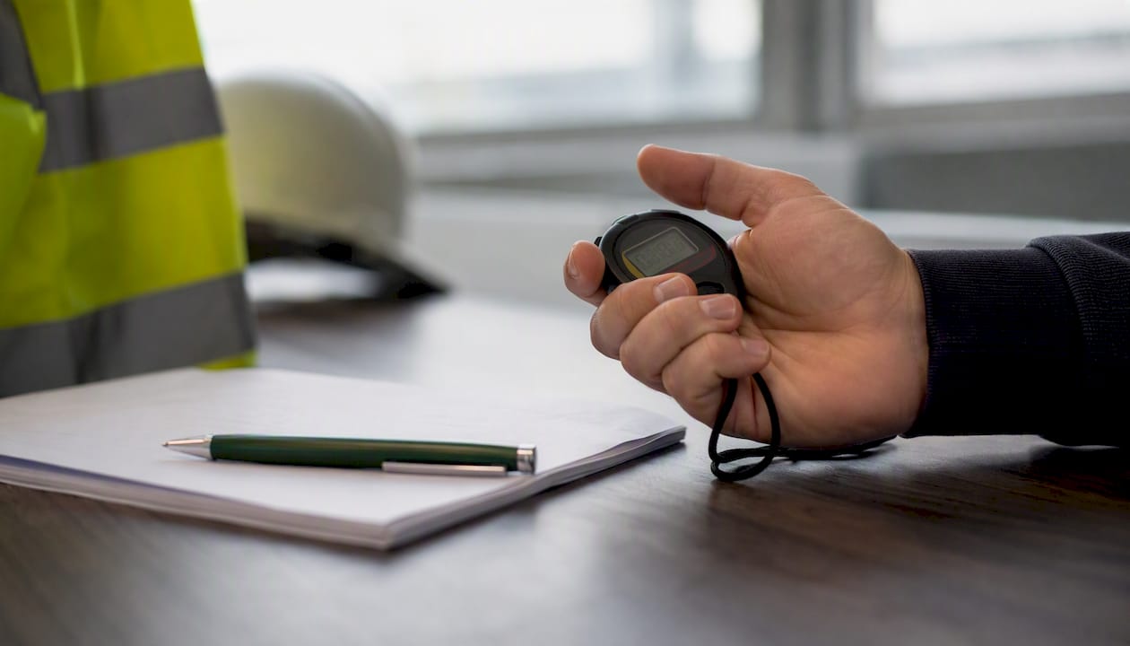 Een hand stelt de timer in voor het VCA-examen.