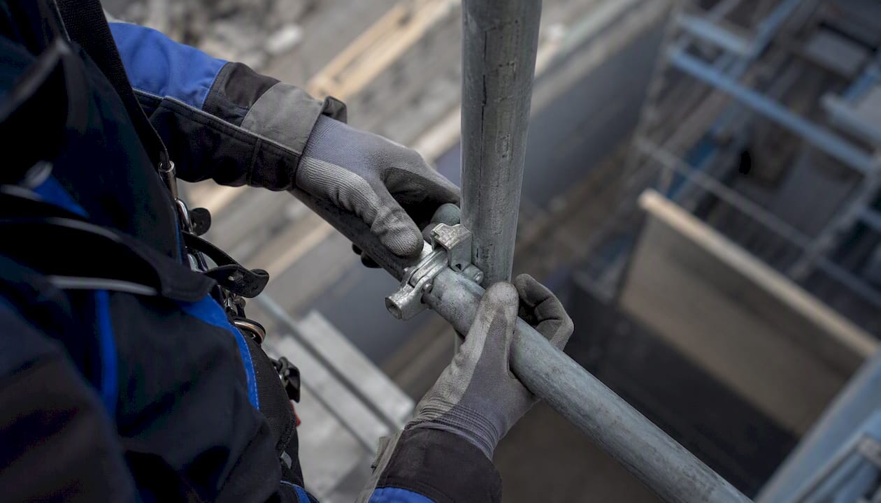 Handen controleren het vergrendelingsmechanisme van de steiger