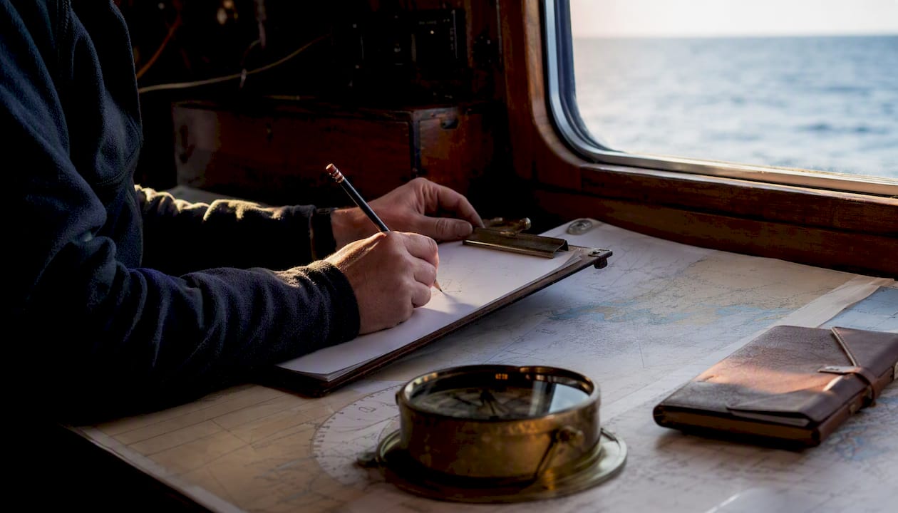 Hands sketching pilotage plan on chart table