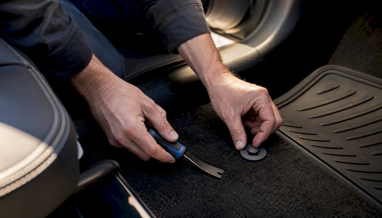 Hands installing floor-mat anchor kit on carpet