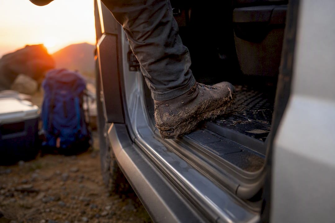 Muddy boot stepping on protective Bronco floor liner