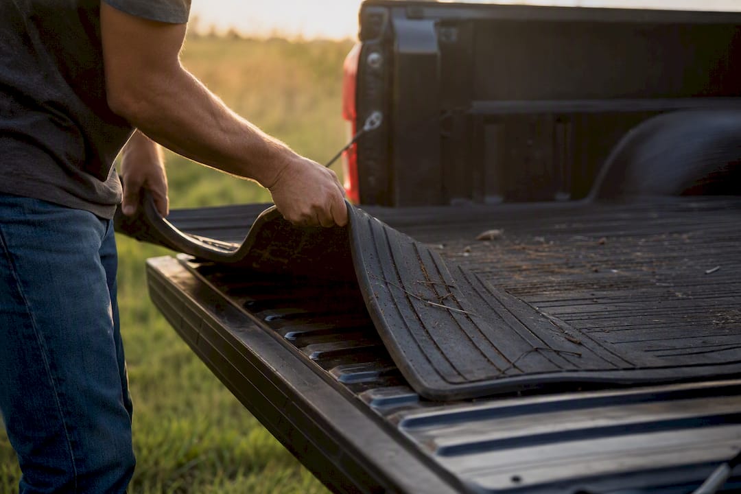 Hands lifting heavy rubber truck bed mat