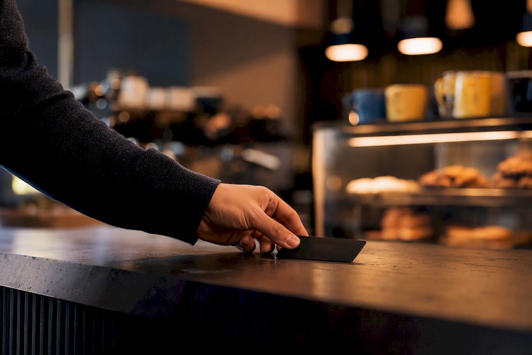 Hand holding credit card over dark desk