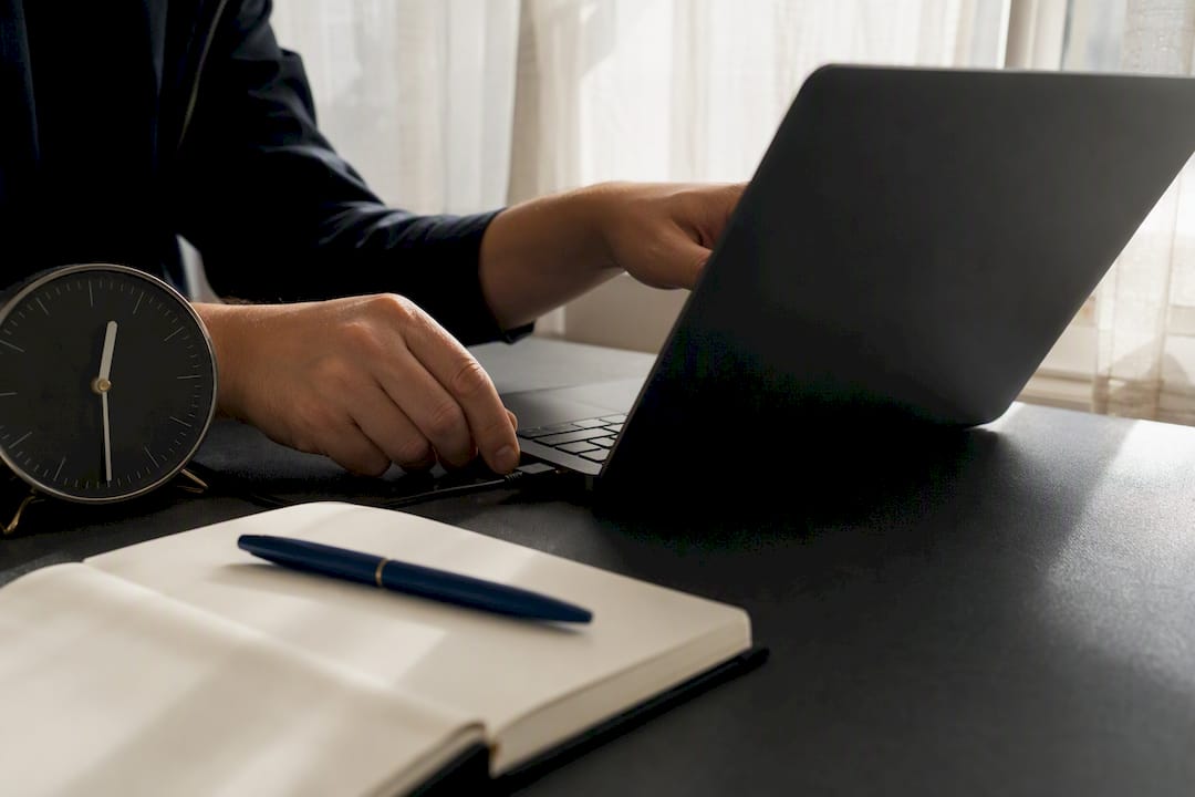Hands connecting laptop power cable on trading desk