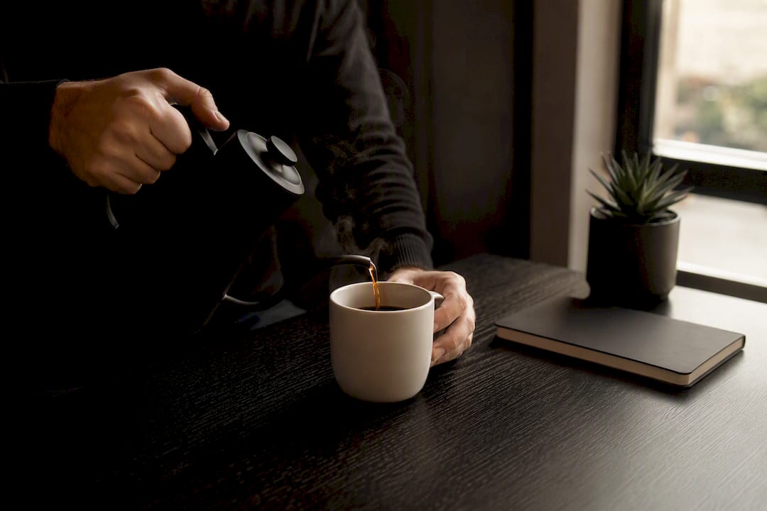 Hands pouring coffee at trading desk