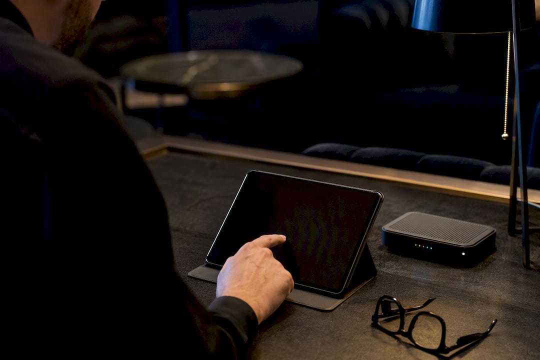 Hand holding tablet near server device on desk
