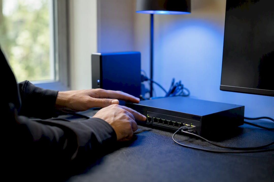 Hands pressing button on network device on dark desk