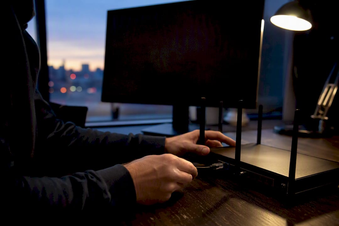 Hands connecting ethernet cable to router on dark desk