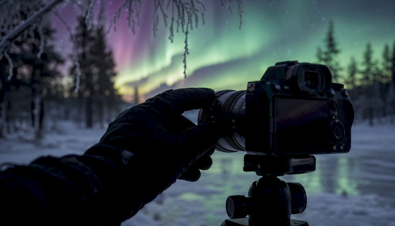 Hand adjusting camera lens focus outdoors at night
