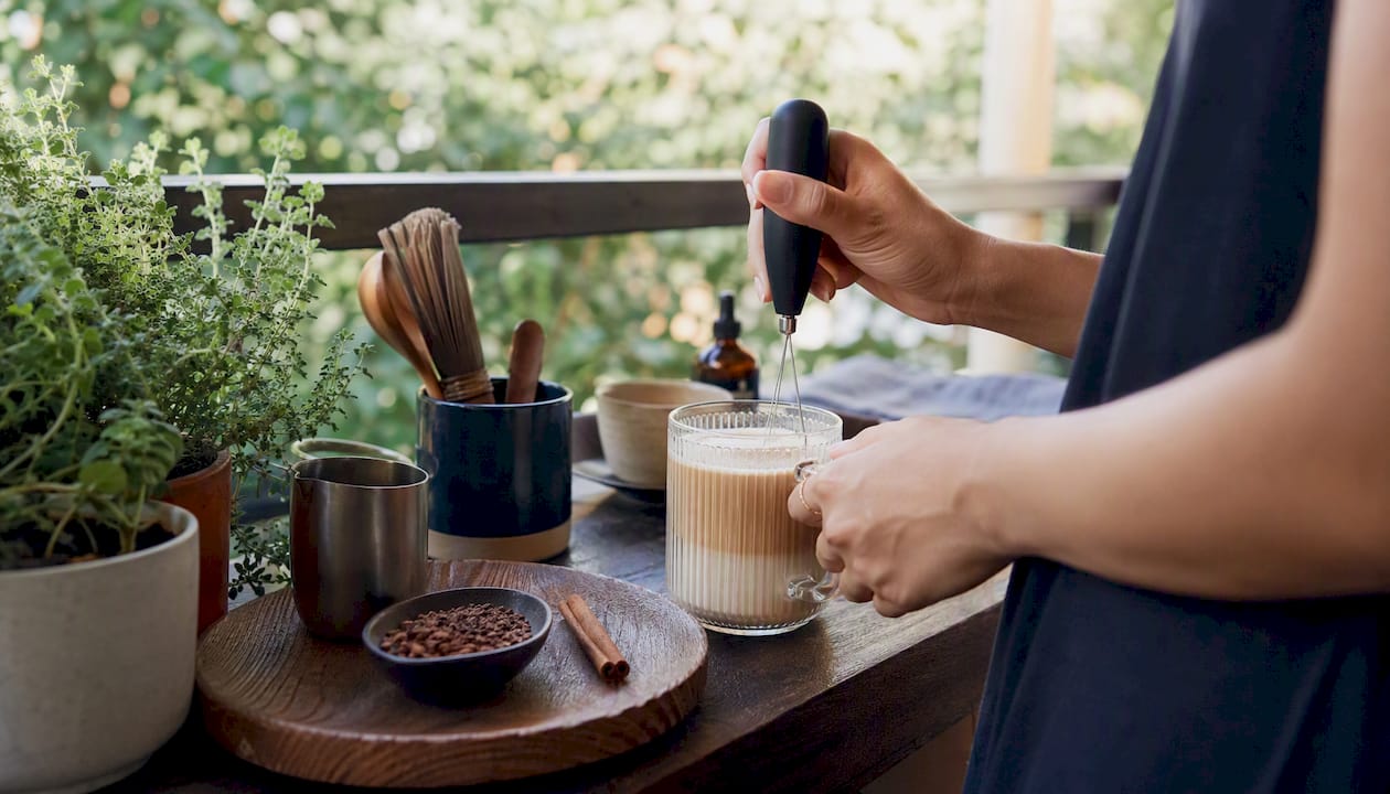 Hands stirring creamy mushroom coffee latte