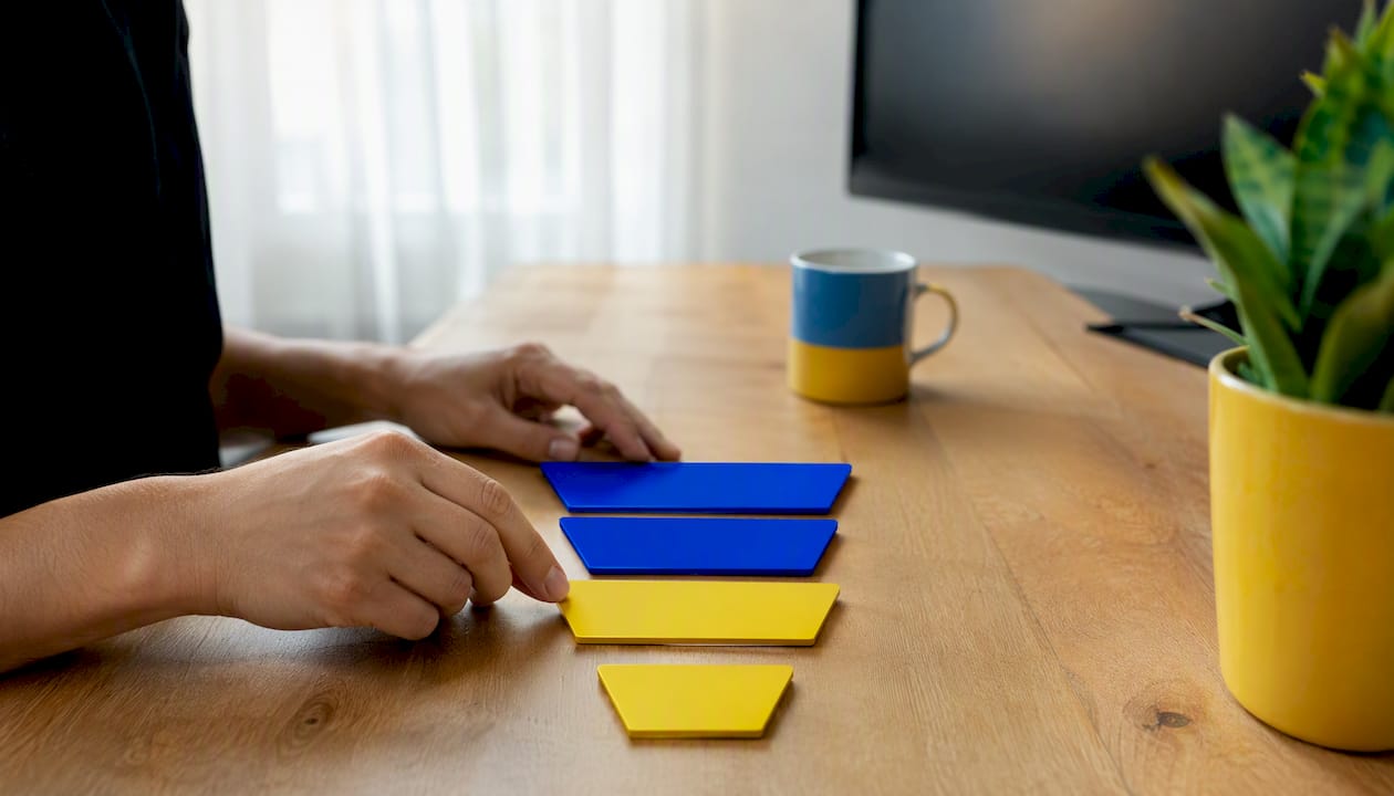 Hands adjusting colored cubes on desk representing funnel metrics