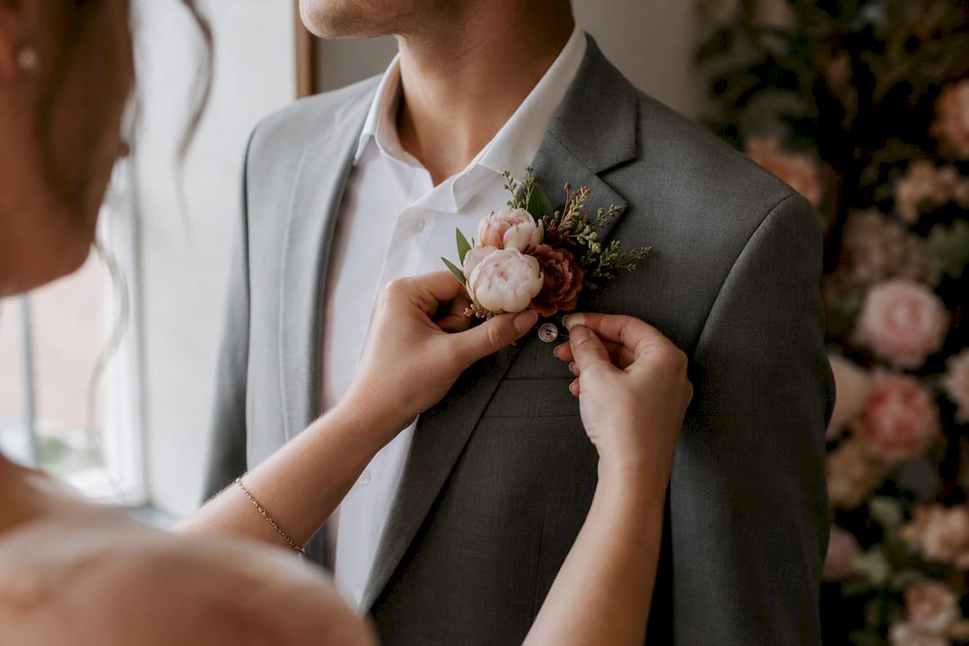 Hands pinning boutonniere on suit lapel