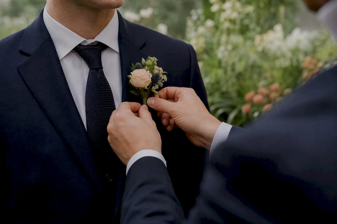 Hands adjusting boutonniere before wedding