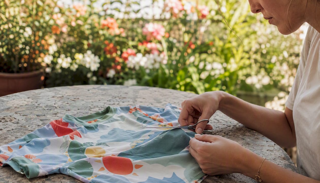 Close-up hands trimming fabric pills with scissors