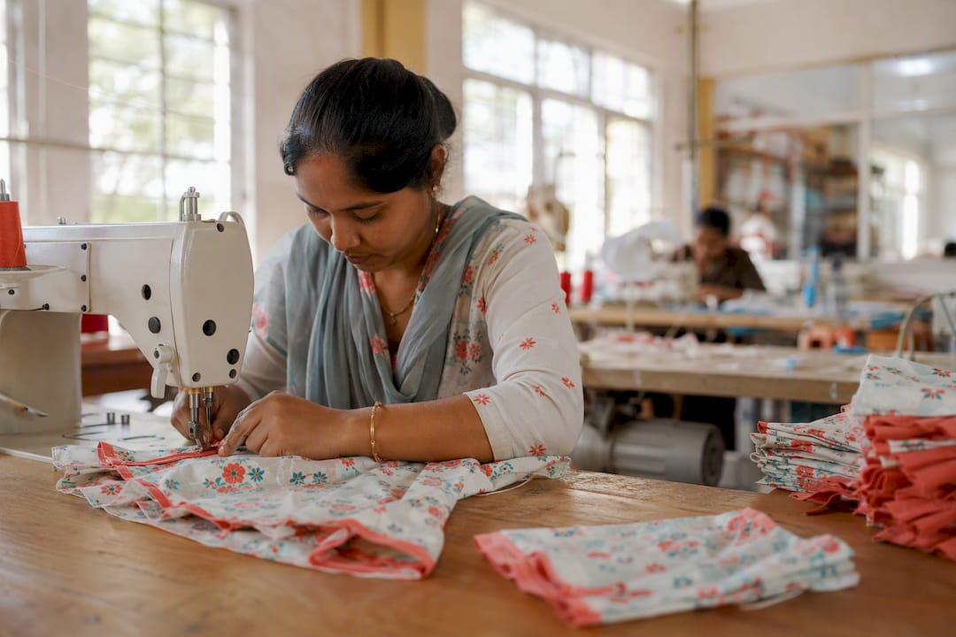 Hands sewing baby clothes in factory