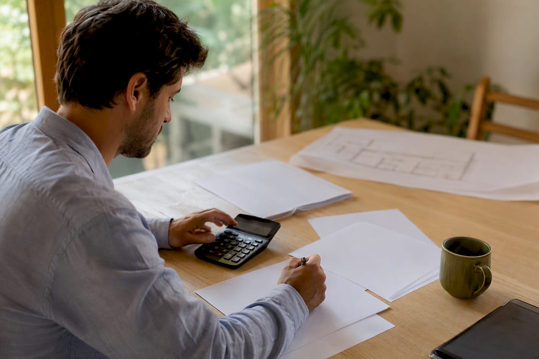 Manos calculando la ganancia por venta de propiedad