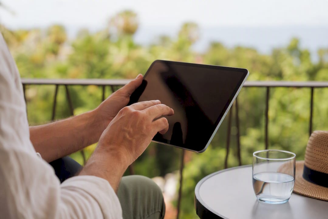 Manos deslizando una tablet con vista a la terraza exterior